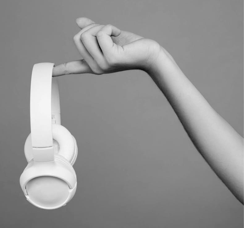 A person holding a white XX59 HEADPHONES with books